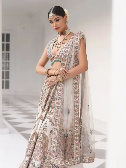 The bride's pose highlights the intricate border of the dupatta and the beautiful flare of the skirt.