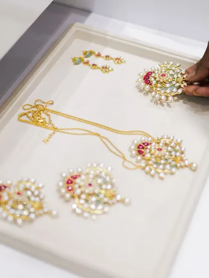 A tray of exquisite, handcrafted jewelry featuring pearls and semi-precious stones, presented to a guest during a private viewing experience.