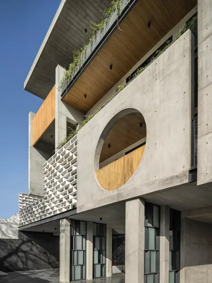 The circular cutout is a key feature of the Swatantra Residence's concrete façade. It shifts across the floors, providing a visual connection between spaces while framing views and bringing natural light deep into the home.