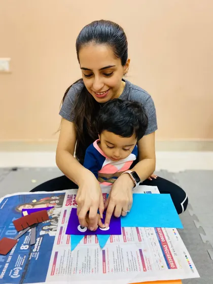 A mother and son work on a craft with googly eyes, adding a playful element to their creation and enhancing fine motor skills.