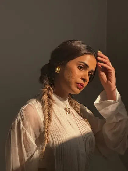 A beautiful behind-the-scenes moment with Shalmali Kholgade. This shot captures the soft, romantic makeup with a berry lip stain and fishtail braids, highlighted by the golden hour light.