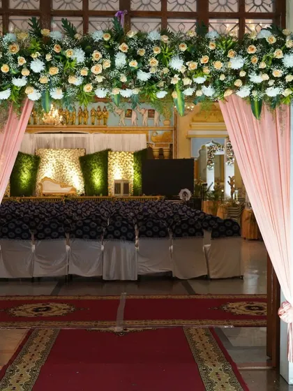 This entrance to a marriage hall features a thick floral arrangement of white and yellow flowers over the doorway. The soft peach drapes on either side add a touch of color and elegance.