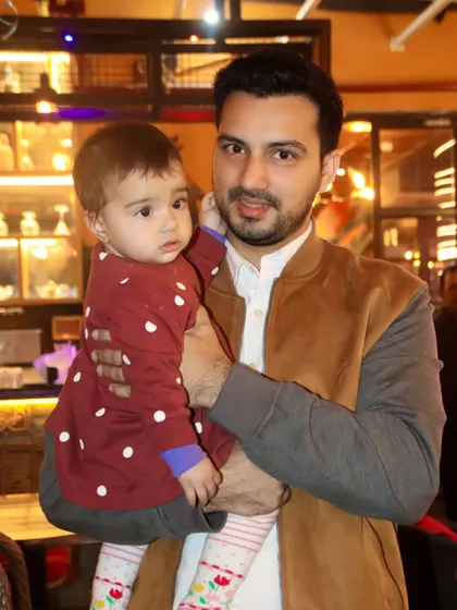 A father holds his young baby, who looks on with a curious expression. A simple, beautiful father-child portrait.