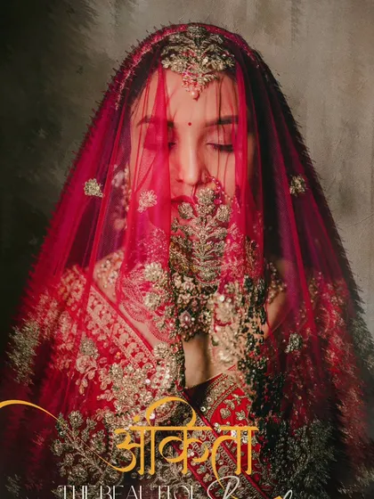An artistic portrait of the bride with her face partially covered by her embroidered red veil, creating a sense of mystery and tradition.