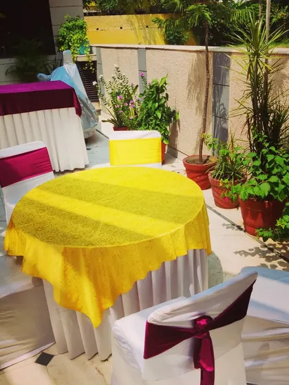 A round table with chairs, covered in bright fabrics. This is a practical solution for guest seating at home functions.