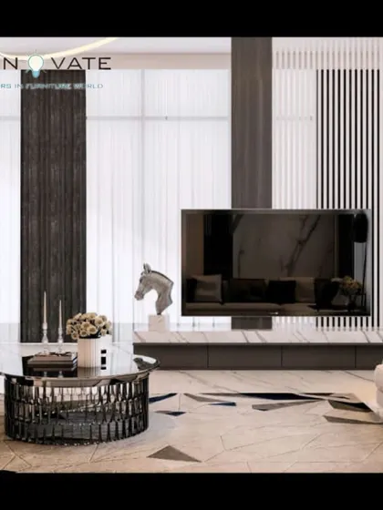 This ultra-modern living room showcases a floor-to-ceiling entertainment unit with contrasting black and white panels. The metallic coffee table and abstract rug complete the high-end, minimalist aesthetic.