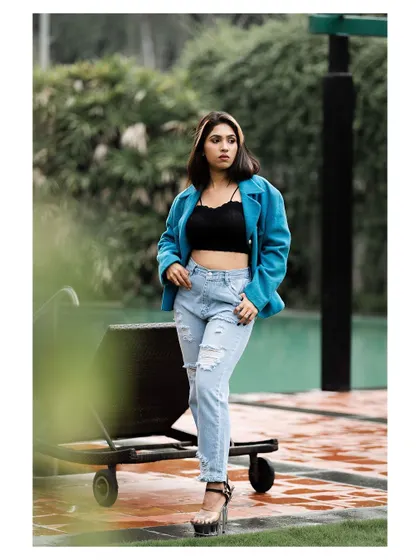 An outdoor fashion shoot with an urban edge. The bright blue jacket stands out against the greenery, creating a fresh and modern look for a model's portfolio.