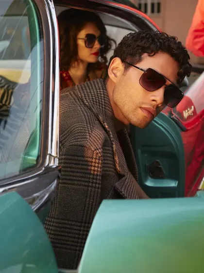 Siddhant Chaturvedi for an IDEE Eyewear campaign, shot with a vintage car. The composition creates a cinematic, story-driven feel, as if it's a still from a classic film.