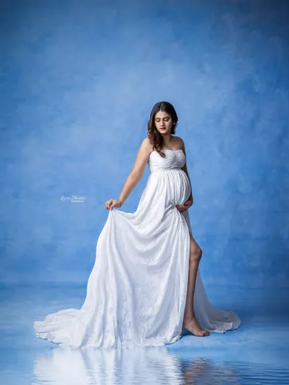 This portrait combines a hand-painted sky backdrop with a water reflection effect, creating a surreal and artistic image. The white lace gown adds a touch of delicate grace.