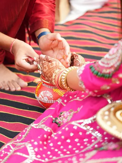 A close-up of the Karwa Chauth rituals, where the intricate mehendi on the hands is clearly visible.