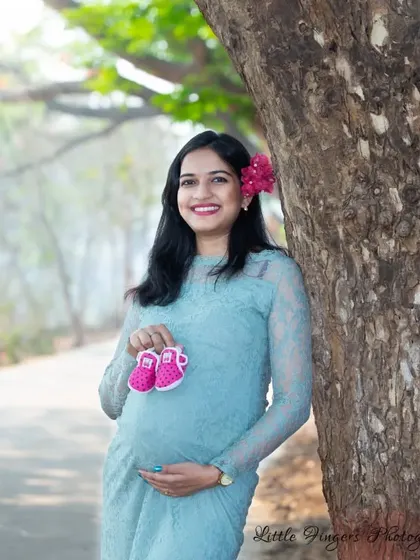 A classic maternity pose with a pair of tiny pink shoes. The mom-to-be's happy smile says it all as she anticipates the arrival of her daughter.