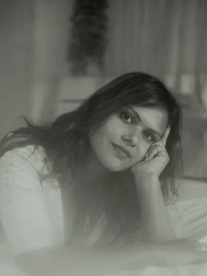 An intimate indoor portrait in black and white. The model's soft smile and relaxed pose, combined with a dreamy, foggy effect, result in a gentle and timeless image.