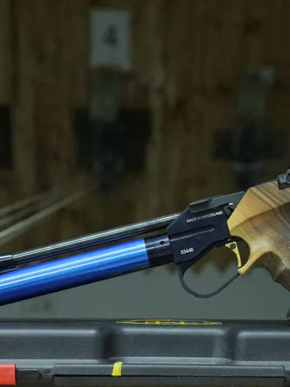 A detailed shot of an Anschutz air pistol with a custom wooden grip, showcasing the precision and quality of the firearms used in our sessions.