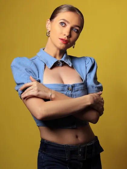 A vibrant studio portrait with a yellow background. The combination of the denim top and the bright backdrop creates a cheerful and energetic mood.