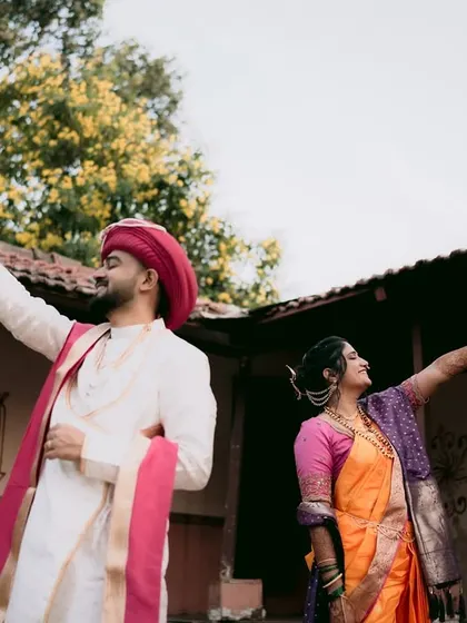 A fun and creative shot of the couple holding up their garlands in a traditional courtyard.