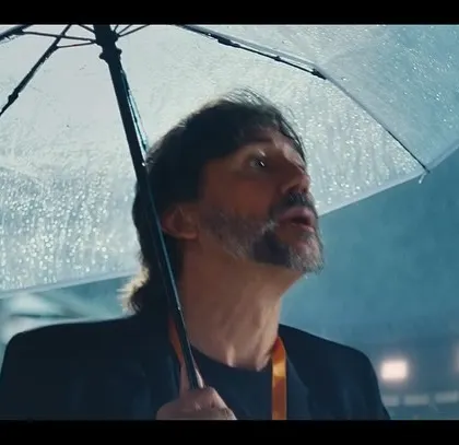 A more contemplative shot of the coach in the rain from the East Bengal FC ad. His simple, dark outfit keeps the focus on his emotional expression.