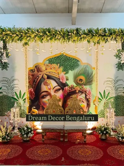 A slightly different angle of the Krishna-themed decor, showing the ornate chairs placed for the ceremony. The details in the artwork and floral arrangements come together perfectly.