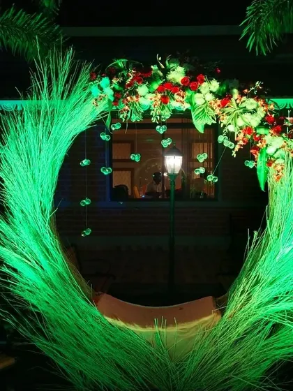 A unique photo booth idea with a circular frame made of illuminated green grass and topped with flowers.