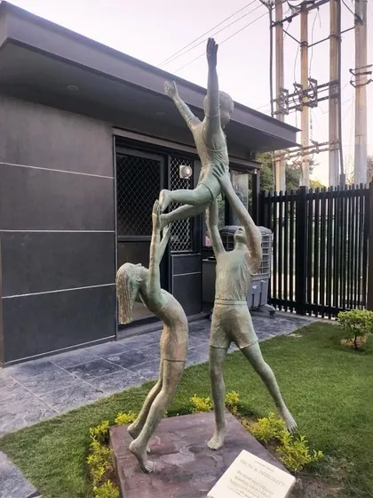A dynamic sculpture of three children playing, capturing a moment of teamwork and joy. This piece is installed in a public park area.