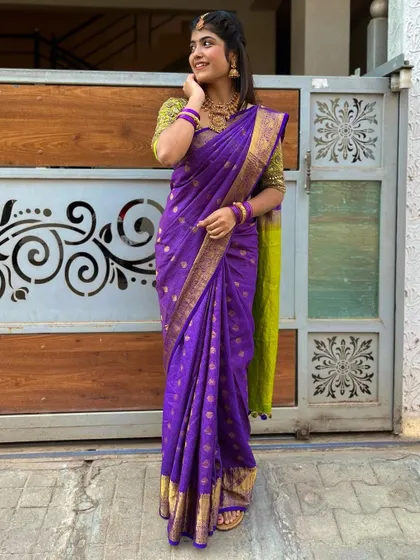 A vibrant purple silk saree with gold butti work, paired with a contrasting lime green blouse.