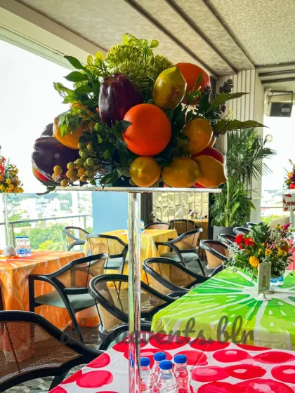The theme extends to the guest tables with fruit-printed tablecloths and tall, elegant centerpieces overflowing with colorful fruits and greenery, ensuring an immersive experience for everyone.