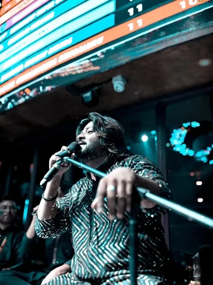 A low-angle shot of me performing at a club gig, with the venue's ticker screen visible above. This shows our experience in various event settings.