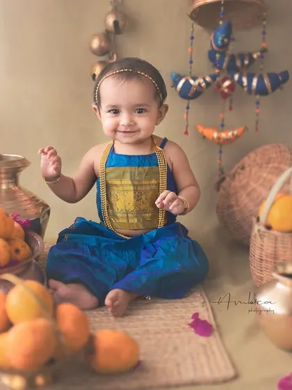 A sweet baby girl in a traditional outfit surrounded by fresh mangoes. This unique concept blends seasonal elements with cultural styling for a truly one-of-a-kind sitter session.