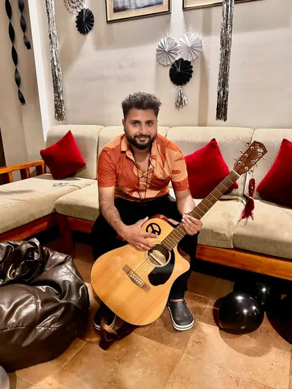 Holding my Fender acoustic guitar, ready for another gig. The peace sign on the guitar reflects the vibe I want to spread through my music.