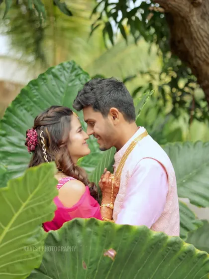 A romantic and candid moment between the wedding couple, captured through a frame of leaves.