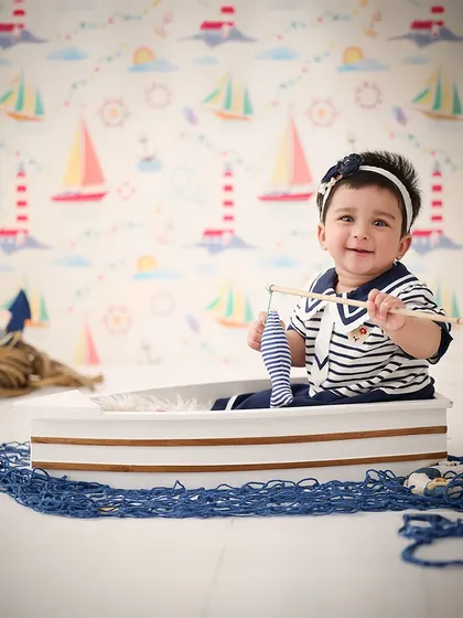 Ahoy, little sailor. This nautical theme with a toy boat and fishing rod is a classic and charming choice for a baby boy's photoshoot.