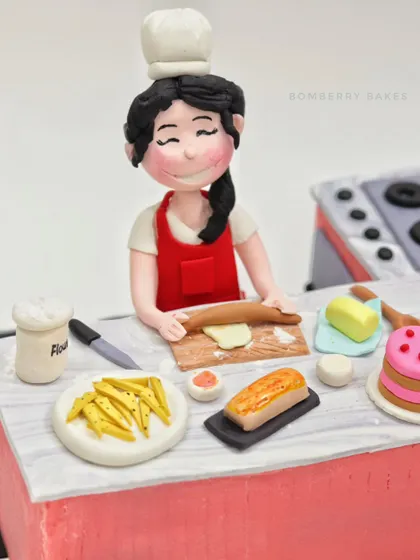 A full view of the "Kitchen Queen" cake, showing the baker figurine at her workstation, complete with a miniature stove in the background.