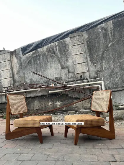 A clean shot of the pair of low chairs against a textured wall, highlighting their minimalist form.