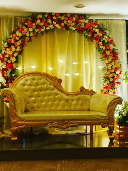 We showered the parents-to-be with love at this beautiful baby shower. The decor features a floral arch over a chaise lounge, set against a backdrop of greenery and elegant drapery.