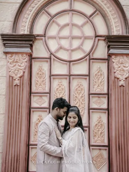 An intimate portrait of a couple in traditional attire, standing before a grand, ornately carved door.