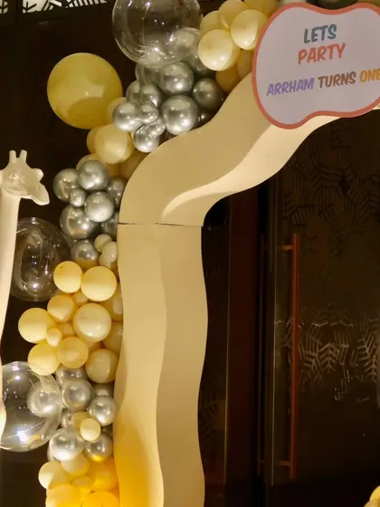 A detail of the entrance arch, showing the "Let's Party" sign and the mix of yellow and metallic silver balloons.