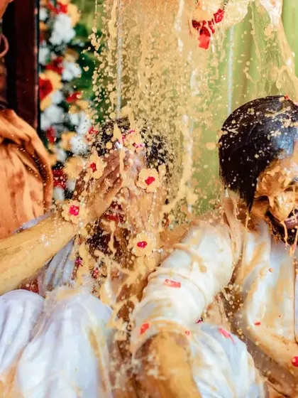 An action-packed photo of a couple getting showered with turmeric and water. We use fast shutter speeds to freeze the motion and capture the excitement.