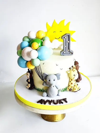 A full view of the sunshine and animals cake, a Chocolate-Peanut butter creation. The balloon cascade is made from chocolate, adding another delicious element.