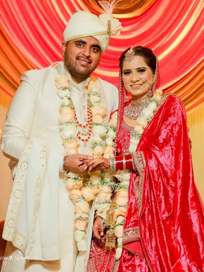 A happy portrait of the newlyweds. The couple is holding hands and smiling, with their beautiful rose garlands adding a touch of tradition and colour.