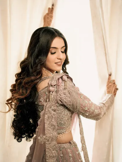 A beautiful portrait of the bride, Sakshi, on her engagement day. The soft, natural light from the window highlights her flowing hair and intricate gown.