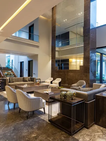 The mirrored column in this double-height space adds a touch of glamour and reflects light, making the already large room feel even more expansive. The minimalist furniture keeps the focus on the architecture.