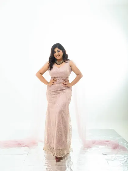 A confident, full-length pose in a modern pink gown. The clean white background puts all the focus on the subject and the elegant silhouette of her dress.
