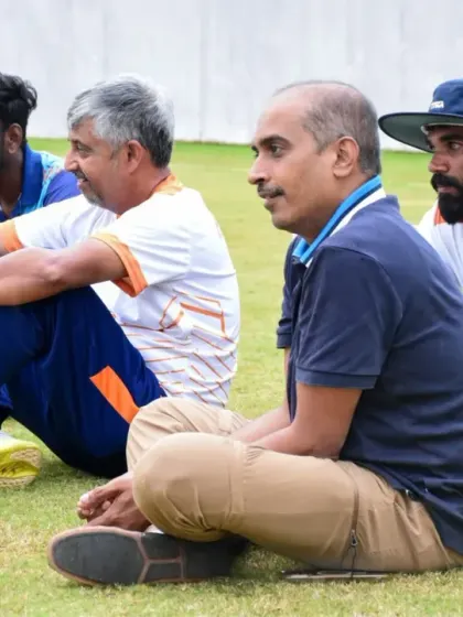 Coaches and players listen intently during a strategy session on the field. This mentorship is crucial for game readiness.