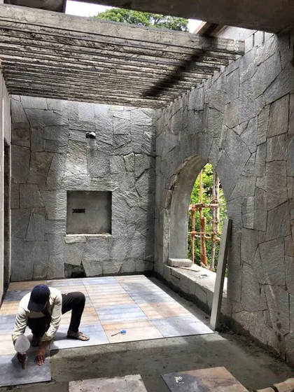 A craftsman at work, carefully laying stone flooring. This is where the magic happens, in the attention to detail and the respect for natural materials.