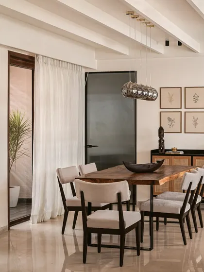 Another view of the dining space, showing the connection to the outdoor patio. The use of sheer curtains and natural materials helps create a seamless indoor-outdoor living experience.