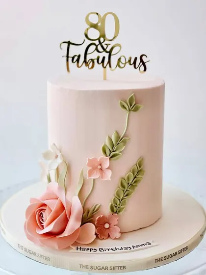 An elegant floral cake for an "80 & Fabulous" celebration. This design features a beautiful, hand-sculpted sugar rose and delicate leaves.