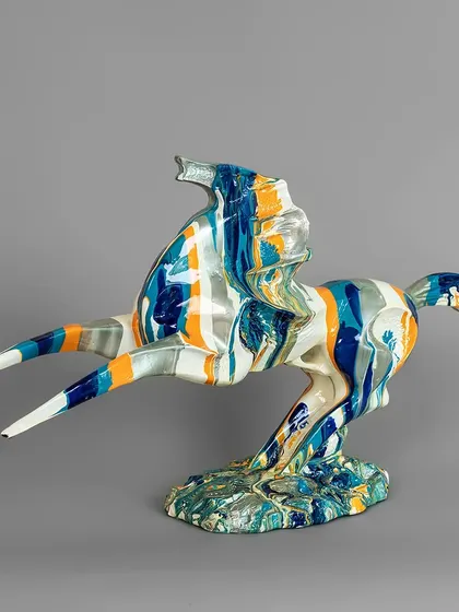 This abstract horse sculpture is a whirlwind of motion and color. The dynamic pose combined with the blue, orange, and white marbled finish makes it a striking centerpiece for a modern home.