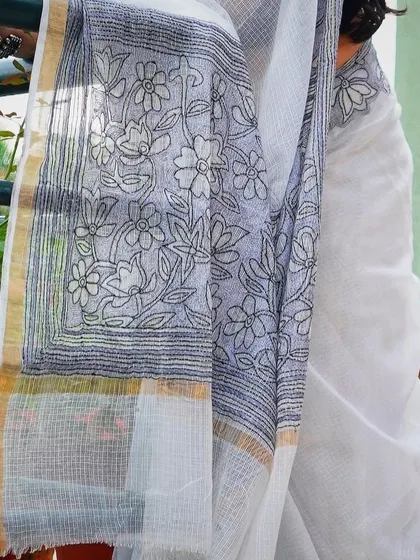 A close-up of the intricate pallu of a contemporary white saree with black floral embroidery.
