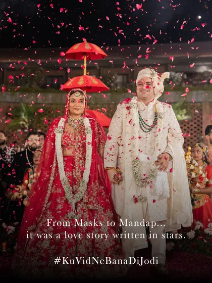 From masks to mandap. This stunning shot of the couple walking down the aisle, showered in petals, marks the culmination of their unique love story.