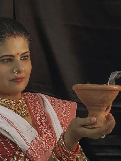 A serene moment during a Durga Pooja themed shoot, holding a traditional dhunuchi. The styling aims to capture the spiritual essence of the festival.