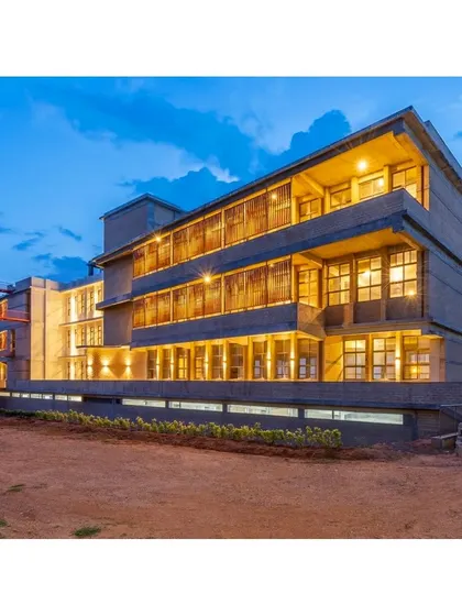 The RSL Office building in Bengaluru at twilight. The facade features parametric terracotta jaali screens that glow from within, showcasing how sustainable design can also be architecturally striking.